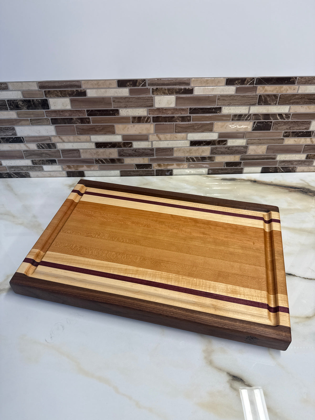 Heritage Cutting Board 18” × 12” × 1.5” — Maple, Walnut, Cherry & Purple Heart | Juice Groove + Hand Holds with brass feet