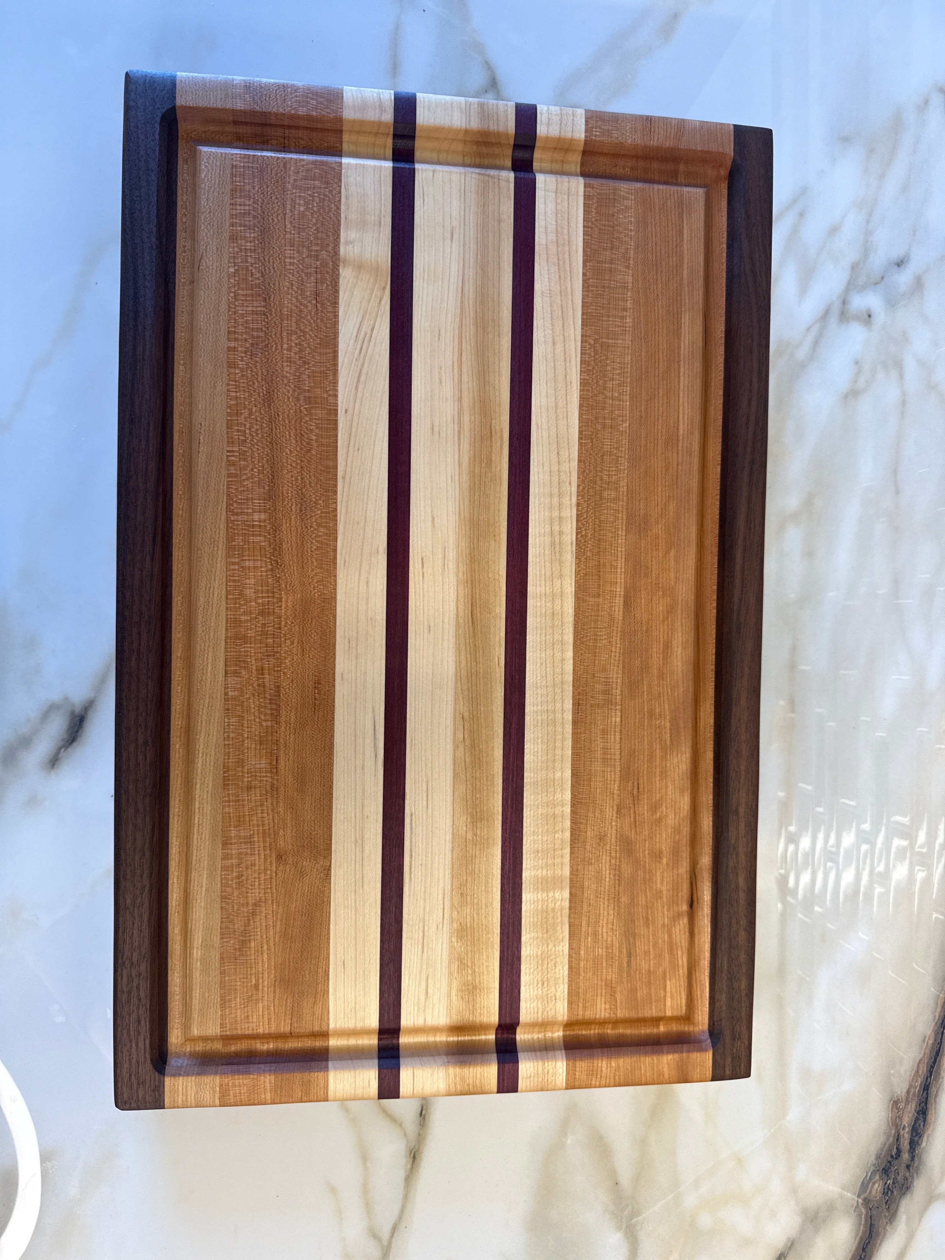 Heritage Cutting Board 18” × 12” × 1.5” — Maple, Walnut, Cherry & Purple Heart | Juice Groove + Hand Holds with brass feet